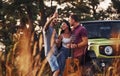 Man holds guitar. Group of cheerful friends have nice weekend at sunny day near theirs green car outdoors Royalty Free Stock Photo