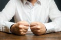 A man holds his closed fists on the table. The end of patience. It is impossible to bear it. An attack of anger, stress.