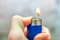 A man holds in his hand a lit gas lighter with a flame, a fire for lighting cigarettes Royalty Free Stock Photo