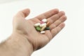 The man holds in his hand pills, vitamins, medicines on a white background. Outstretched hand with handful of pills