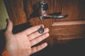 A man holds in his hand a small light broken key against the background of a door lock Royalty Free Stock Photo