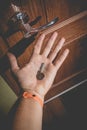 A man holds in his hand a small light broken key against the background of a door lock Royalty Free Stock Photo