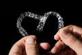 A man holds in his hand transparent aligners plastic braces retainers for straightening teeth on a black background Royalty Free Stock Photo