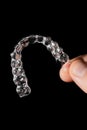 A man holds in his hand transparent aligners plastic braces retainers for straightening teeth on a black background Royalty Free Stock Photo