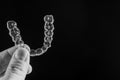 A man holds in his hand transparent aligners plastic braces retainers for straightening teeth on a black background Royalty Free Stock Photo