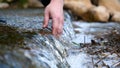 A man holds his hand washes his hands in the fountain water, clearing them of dirt, and holding the water of the waterfall in Royalty Free Stock Photo