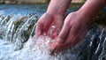 A man holds his hand washes his hands in the fountain water, clearing them of dirt, and holding the water of the waterfall in Royalty Free Stock Photo