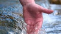 A man holds his hand washes his hands in the fountain water, clearing them of dirt, and holding the water of the waterfall in Royalty Free Stock Photo