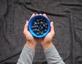 A man holds in his hands fresh blueberries in a bowl on black background Royalty Free Stock Photo