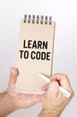 A man holds in his hands a pen and a chatter with the inscription - Learn To Code