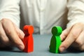 A man holds in his hands the red and green figures of people facing each other. Conflict resolution, conflict of interest.