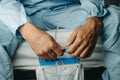 man holds his urine drainage bag sitting in bed