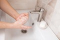 A man holds his washing hands under running water in the bathroom. A close-up. Hand hygiene .