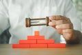 Man holds hourglass in his hand above on red block pyramid. The concept of distribution of time for work