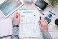 Man holds invoice of water usage over desk