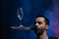 A man holds a knife in his mouth and keeping vine glass in balance. Unique circus skill. Royalty Free Stock Photo