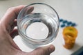 Man holds with left hand a glass of water next to a pill bottle Royalty Free Stock Photo