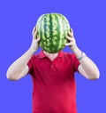 A man holds at the level of the head of a ripe tasty watermelon. Watermelon instead of the head. Advertising of watermelons