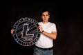 A man holds a litecoin coin in his hands as a symbol of technology