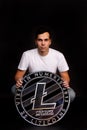 A man holds a litecoin coin in his hands as a symbol of technology