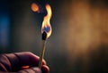 man holds a match in his hand. burning fire on a piece of wood.