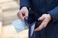 Man holds a medical mask and empty wallet without money. Bankruptcy and unemployment resulting from the global coronavirus