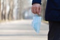 Man holds medical mask walking in park. World coronavirus epidemic concept