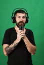 Man holds microphone on green background. Singer with beard