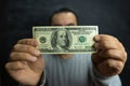 A man holds money, a hundred-dollar bill in the hands of a man in front of his face Royalty Free Stock Photo