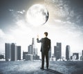 Man holds the Moon like a balloon at city background