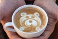 A man holds a mug of coffee with a pattern of a bear