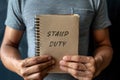 A man holds a notebook with the words Stamp duty. Taxes assessed during the transfer of real estate between two parties. Buying