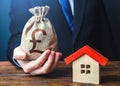 Man holds out a british pound sterling bag near the house. Home purchase, invest in real estate. Favorable terms and conditions, Royalty Free Stock Photo