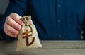 A man holds out a Turkish lira money bag. Deposits and savings.