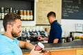 Man holds paper cup with coffee barista guy stand on background. Client got his drink. Drinks to go useful option in