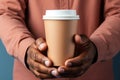 A man holds a paper cup for coffee in his hands, a mockup for manufacturers of branded cups for drinks. Royalty Free Stock Photo