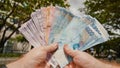 A man holds Philippine money bills in his hands.