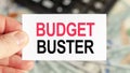 A man holds a piece of paper with the text: BUDGET BUSTER. Business and finance concept