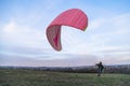 Man holds pink paraglider flying in wind outdoor