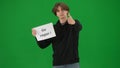 A man holds a poster with an inscription go vegan and shows a thumbs up. Male vegan demonstrator in studio on green