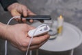 Man holds a power bank in his hands and charges a smartphone against a concrete wall Royalty Free Stock Photo