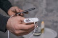 Man holds a power bank in his hands and charges a smartphone against a concrete wall Royalty Free Stock Photo