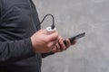 Man holds a power bank in his hands and charges a smartphone against a concrete wall Royalty Free Stock Photo