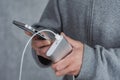 A man holds a power bank in his hands and charges smartphone on a gray background