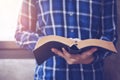 A man holds and reading bible book over the concrete wall with window light Royalty Free Stock Photo