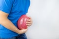 Bloating and flatulence concept. The man holds a red balloon near the abdomen, which symbolizes gas problems. Intestinal tract and