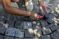 A man holds a red-black rubber mallet in his hand and knocks it on the surface of gray granite stones on the sidewalk, top view. Royalty Free Stock Photo