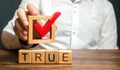 A man holds a red check mark over word True. Confirm the veracity and truth. Fight against fake news hostile propaganda Royalty Free Stock Photo