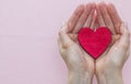 Man holds a red heart in his palms on a pink background Royalty Free Stock Photo