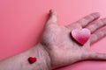 Man holds a red heart in his palms on a pink background Royalty Free Stock Photo